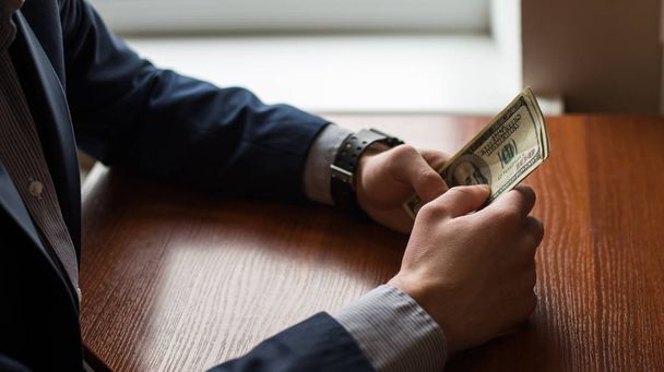 Geschäftsmann Hand ergreift Geld, uns Dollar (usd) bills.man im Anzug. Holz Hintergrund - Foto, Bild