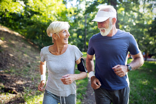 Happy fit senior couple exercising in outdoor park - Photo, Image