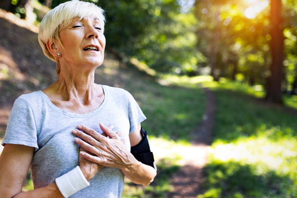 Senior woman athlete have sore left chest pain dizziness - Zdjęcie, obraz