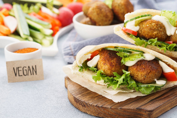 Pita breads with falafel, fresh vegetable sticks and sauce. - Foto, afbeelding