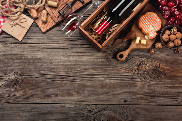 Vakantie diner instellen met rode wijn en kaas op rustieke hout afromen. Bovenaanzicht met ruimte voor uw groeten. - Foto, afbeelding