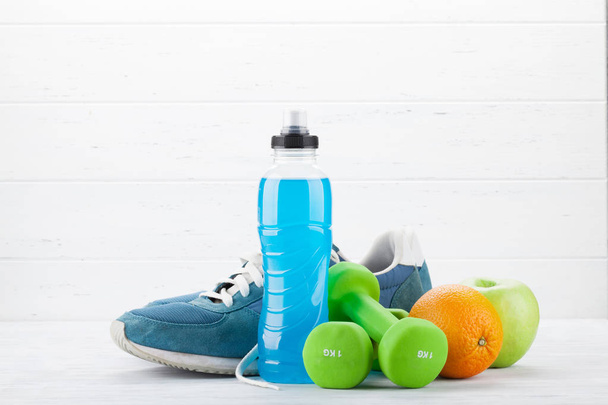 Dambıl ve içki şişesi üzerinde ahşap masa meyve ile spor ayakkabıları. Fitness ve sağlıklı gıda kavramı.   - Fotoğraf, Görsel