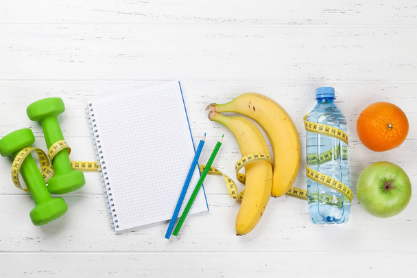 Αλτήρες με φρούτα και σημειωματάριο με μπουκάλι ποτό, κάτοψη, Fitness και υγιεινή τροφίμων έννοια.   - Φωτογραφία, εικόνα