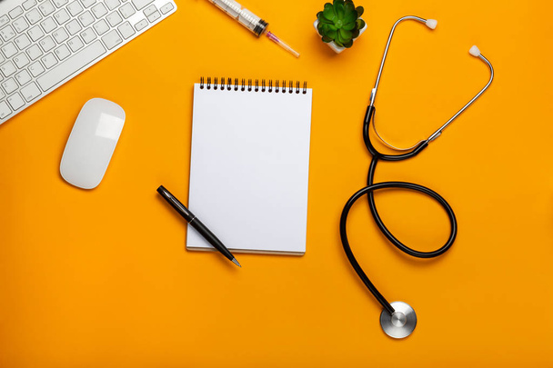 Vue du dessus d'une table de médecin avec bloc-notes et stylo stéthoscope, clavier, prescription et pilules, une tasse de café sur fond jaune
 - Photo, image