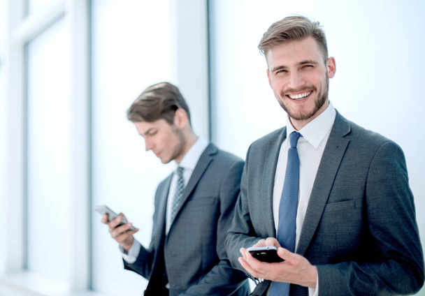 successful employees using their smartphones sitting in the office lobby - Фото, изображение