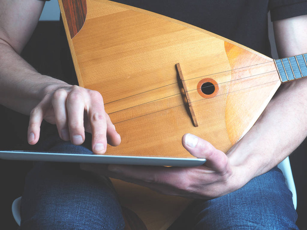 Musician with a balalaika and tablet computer - Valokuva, kuva