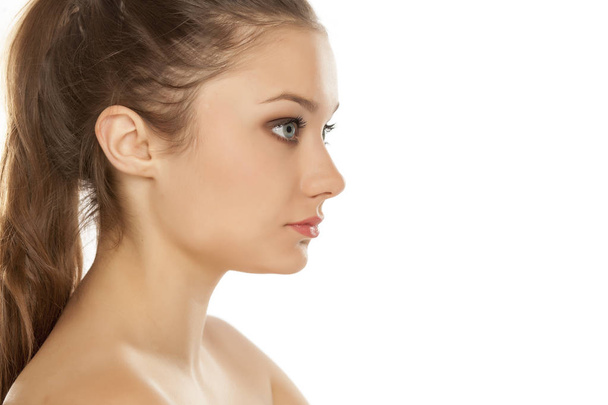 Vista de perfil de una joven con maquillaje sobre un fondo blanco
 - Foto, imagen