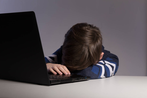 Close-up foto van pesten tiener jongen gevoel overstuur infront van de computer. Gestresst trieste jongen is pesten door zijn klasgenoten. - Foto, afbeelding
