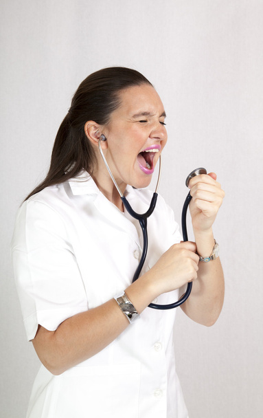 χαριτωμένο γυναίκα γιατρό με ένα στηθοσκόπιο τραγουδά - Φωτογραφία, εικόνα