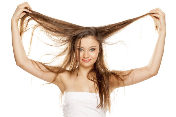 Young blonde showing her long straight hair on a white background - Fotografie, Obrázek