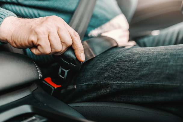 Primo piano di uomo anziano fissaggio cintura di sicurezza mentre seduto in macchina
. - Foto, immagini