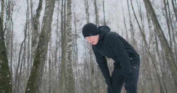 Genç bir adam bir dürtmek kış orman yorgun ve onun nefes yakalamak için durdu. Onun gücü yeniden elde etmek ve yorgunluk üstesinden geldi ve çalışmaya devam etti. Azim ve zayıflık üstesinden - Video, Çekim
