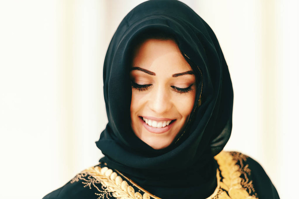 Close up of beautiful muslim woman with toothy smile looking down. - Photo, Image