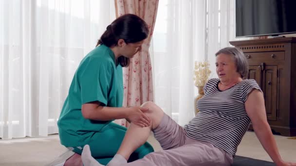 Nurse giving leg massage to senior woman in a retirement home. Physiotherapist nurse helping an elderly women physical rehabilitation at home. Slow motion 4k hand held movement - Footage, Video