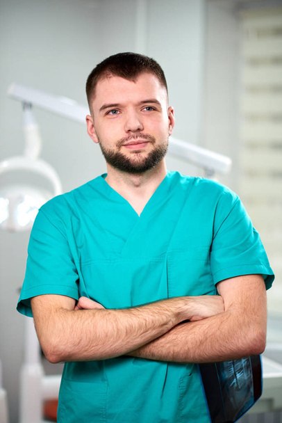 Caucasian male dentist holding xray in hands and smiling - Фото, изображение
