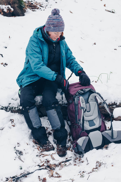 Chica joven sentada con mochila en el bosque de invierno
 - Foto, Imagen