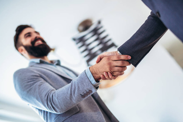 Молодые бизнесмены пожимают руки в офисе. Отделка suc
 - Фото, изображение