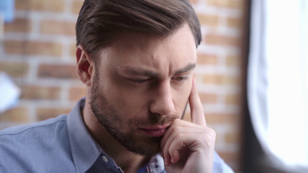 Businessman in shirt thinking, touching face with hand and thoughtfully looking away - Footage, Video