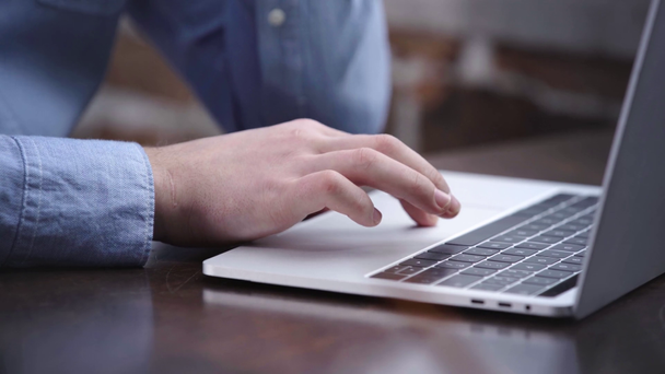 Vista parziale di uomo d'affari in camicia blu digitando sulla tastiera del computer portatile e utilizzando touchpad
 - Filmati, video
