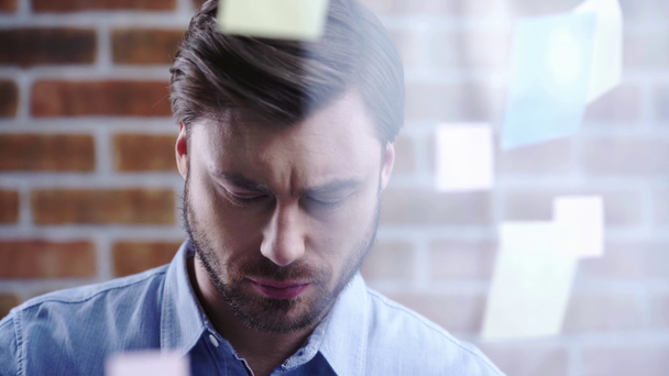 Σοβαρό επιχειρηματία σε μπλε πουκάμισο ανάγνωση και συγκινητικό κολλώδεις σημειώσεις με στυλό - Πλάνα, βίντεο