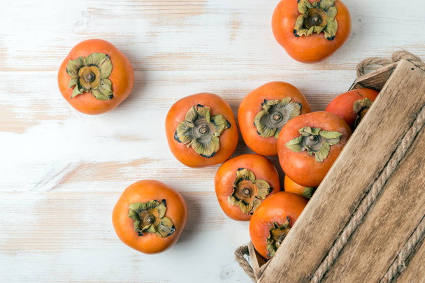 Delicious fresh persimmon fruits on wooden table. - Fotoğraf, Görsel