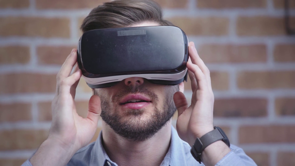 Smiling man with wristwatch wearing vr headset, looking around and stretching out hand - Filmagem, Vídeo