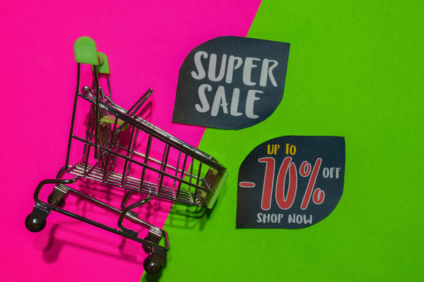 Super Sale und bis zu -70% Rabatt auf Shop jetzt Text und Warenkorb. Rabatt- und Werbekonzept auf buntem Hintergrund - Foto, Bild