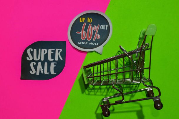 Super Sale und bis zu -60% Rabatt auf Shop jetzt Text und Warenkorb. Rabatt- und Werbekonzept auf buntem Hintergrund - Foto, Bild