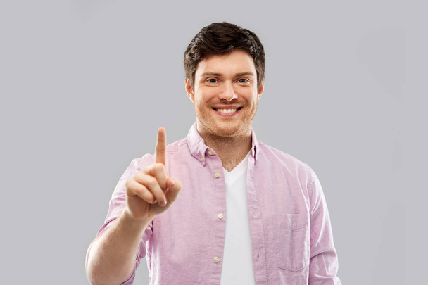 молодой человек показывает пальцем на сером фоне
 - Фото, изображение