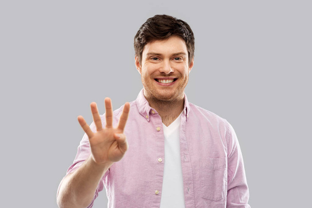 young man showing four fingers over grey - Фото, зображення