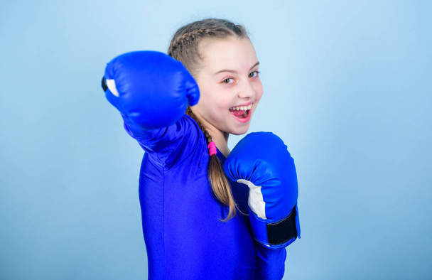 With great power comes great responsibility. Boxer child in boxing gloves. Girl cute boxer on blue background. Rise of women boxers. Female boxer change attitudes within sport. Feminism concept - Foto, afbeelding