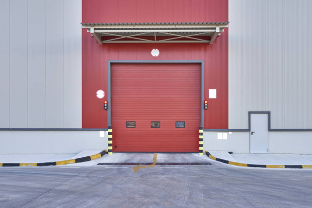 Puerta de obturación o puerta enrollable de color rojo, en el sitio de construcción de nueva fábrica
  - Foto, Imagen