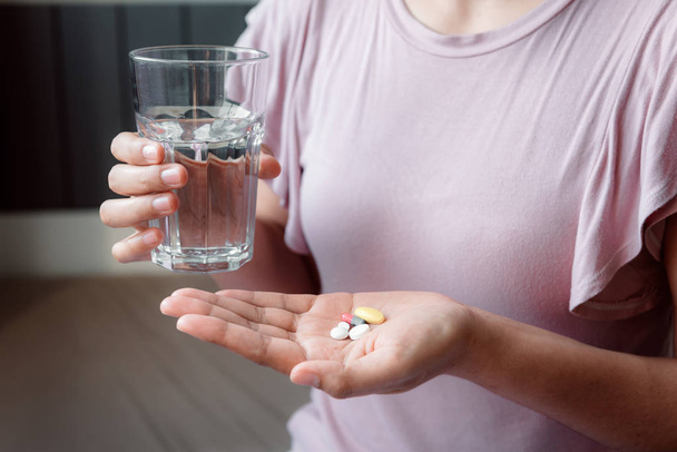Lähikuva nainen käsi on tilalla lasi vettä ottaen pillereitä
 - Valokuva, kuva