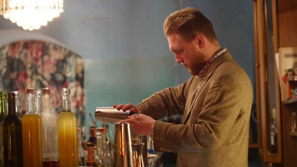Jonge professionele barman gieten van een drankje in de shaker - Foto, afbeelding