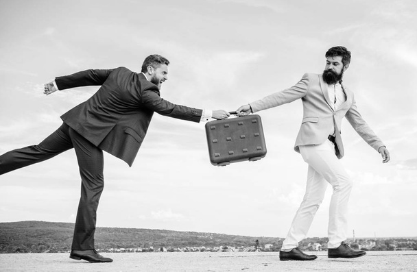Men suits handover briefcase. Rascal racketeer extortionist cheating business transaction. Risky transaction. Fraud and extortion concept. Businessman takes away briefcase from business partner - Foto, imagen