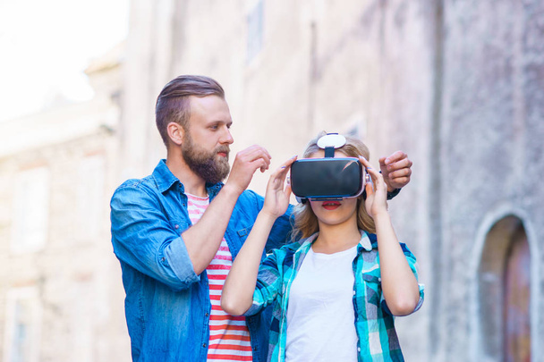 Couple walking in the street in augmented or virtual reality headset. VR, AR, entertainment devices and futuristic technology concept. - Photo, image