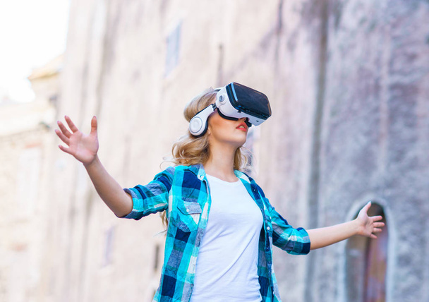 Girl walking in the street in augmented or virtual reality headset. VR, AR, entertainment devices and futuristic technology concept. - Photo, Image