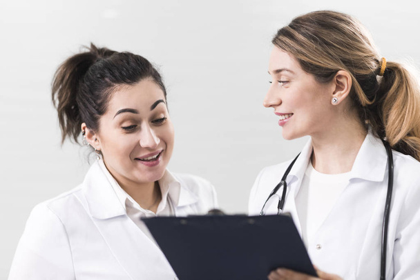 Beyaz kat diş hekimliği Merkezi Birbirinizle konuşmak giymiş iki kadın yardımcıları - Fotoğraf, Görsel