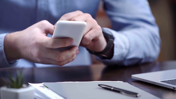 Oříznutý pohled podnikatel v modré košili pomocí smartphone na pracovišti - Záběry, video