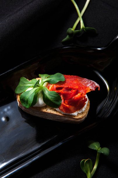 Présentation par l'auteur de bruschetta au fromage à la crème, verdure et chorizo sur un fond sombre et élégant
 - Photo, image