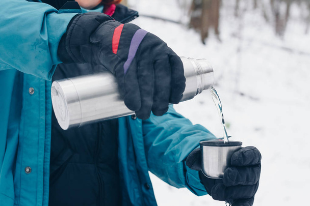 Hiker pours tea from the thermos in the winter - Foto, imagen