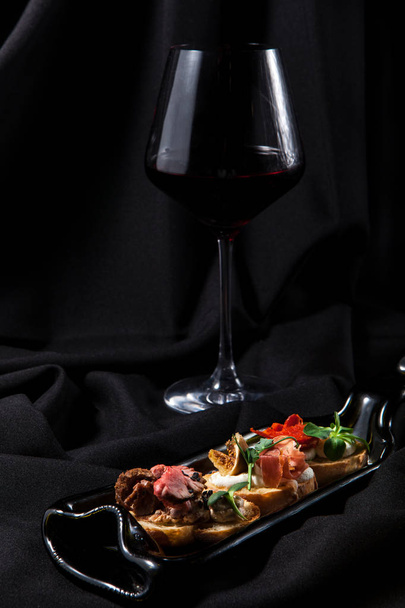 Bruschetta karanlık şık arka plan üzerinde şarapla üçlüsü - Fotoğraf, Görsel