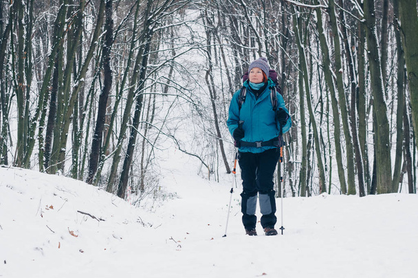 冬の森で上り坂のハイキングのバックパックを持つ少女 - 写真・画像