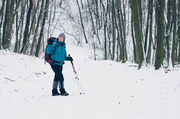 A hátizsák fiatal lány megfordul tartózkodó az úton, a téli erdő - Fotó, kép