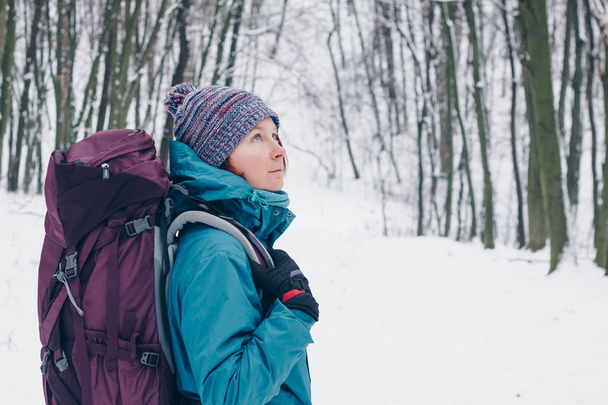 Fiatal lány, a hátizsák úgy néz, ki tartózkodik a téli erdő. Nézd meg a jobb oldalon - Fotó, kép