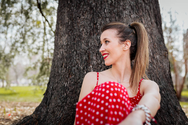 Giovane donna bionda sorridente con abito lungo rosso e una treccia
 - Foto, immagini