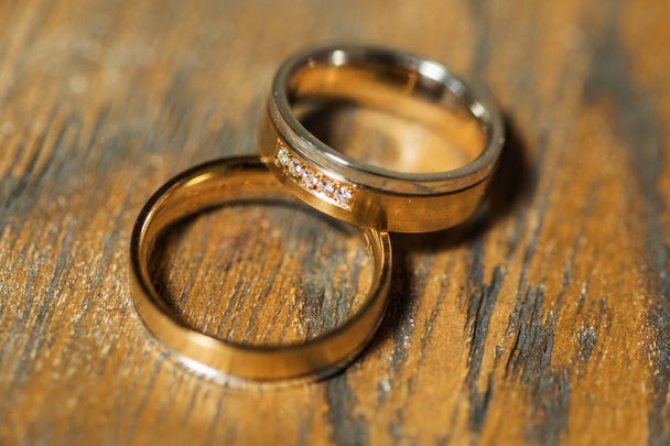 Detalles de la mañana del día de la boda. dos anillos de boda de oro están en la mesa de madera marrón
 - Foto, Imagen