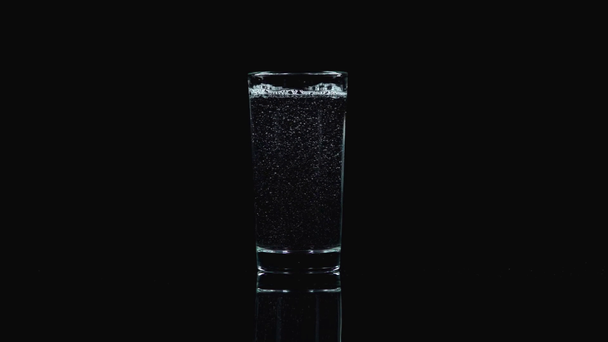 Studioaufnahme von klarem Wasser, das in transparentes Glas gegossen wird, isoliert auf Schwarz - Filmmaterial, Video