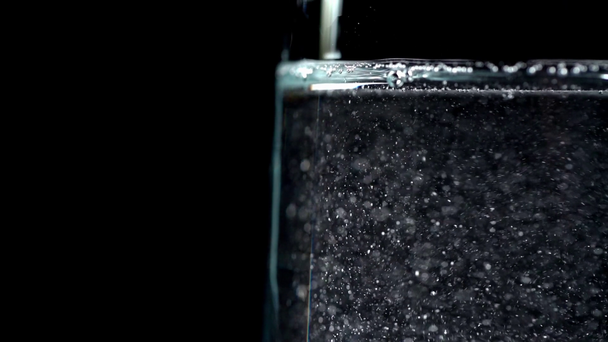 primer plano vista de agua clara vertiendo en vidrio transparente aislado en negro
 - Imágenes, Vídeo