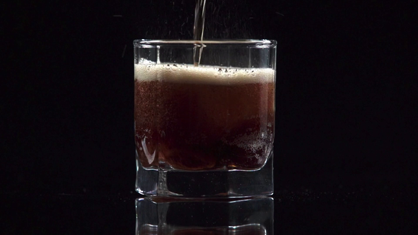 sesión de estudio de agua con gas vertiendo en vidrio transparente con cubitos de hielo aislados en negro
 - Metraje, vídeo